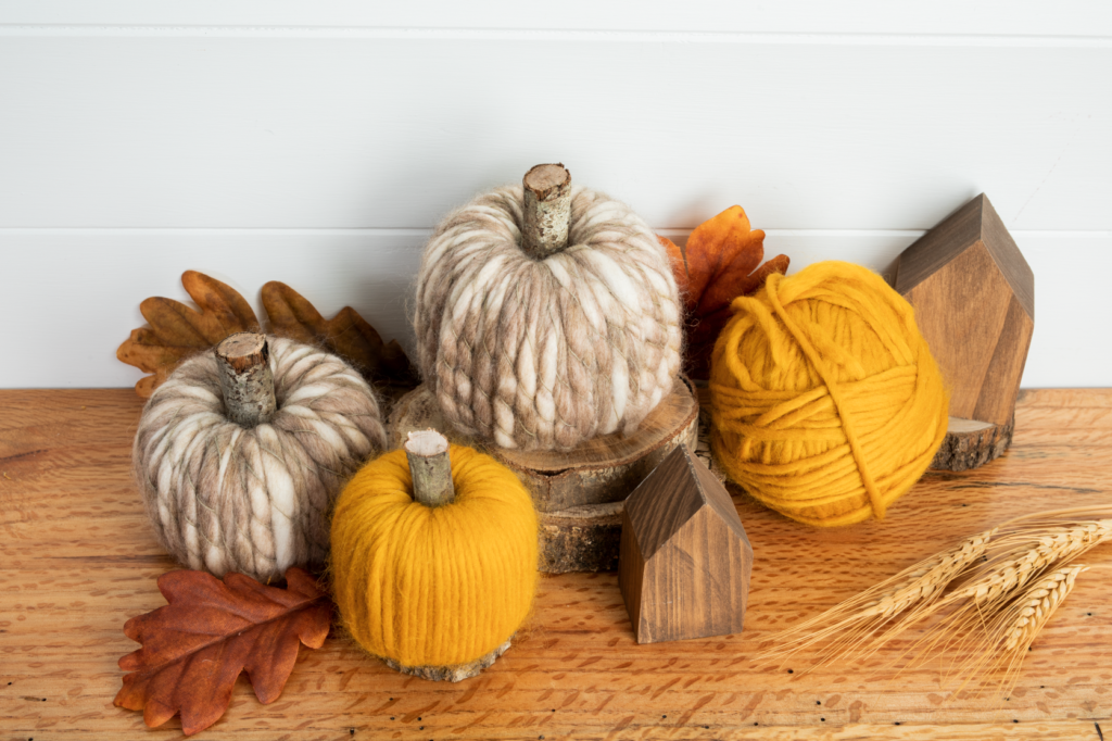 yarn pumpkins on a wood table with little wood houses